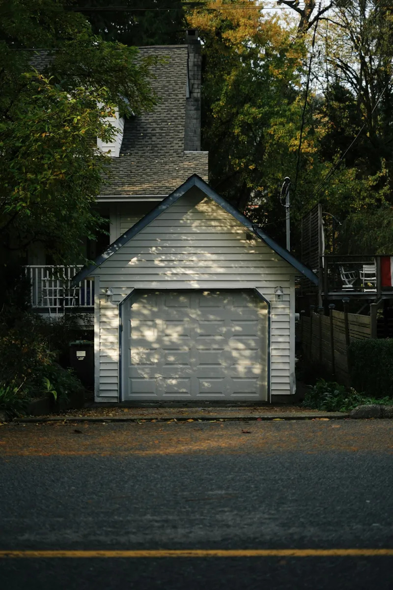 Older detached single-car garage with a white door at the end of a driveway